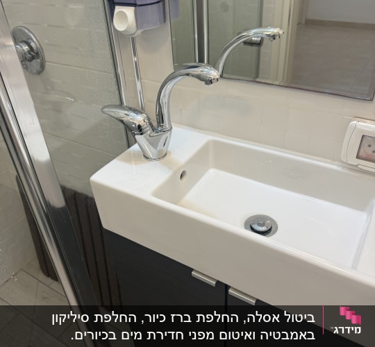 כיור עם ברזים ומתקן סבון בחדר אמבטיה